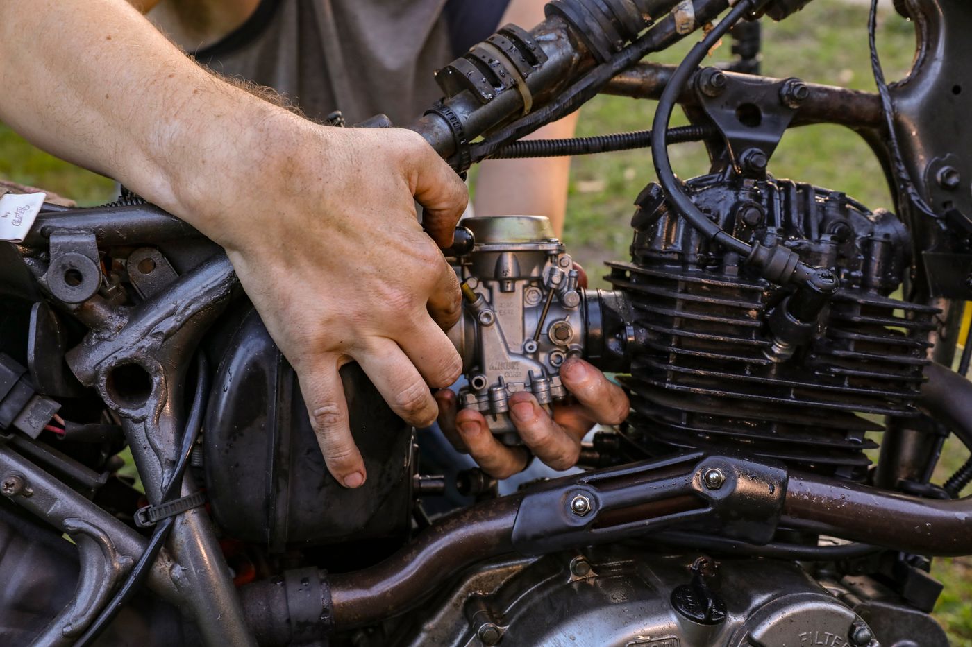 Close-up of hands servicing a motorcycle engine